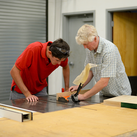 Art professor Phillip Shore sculpting wood with student