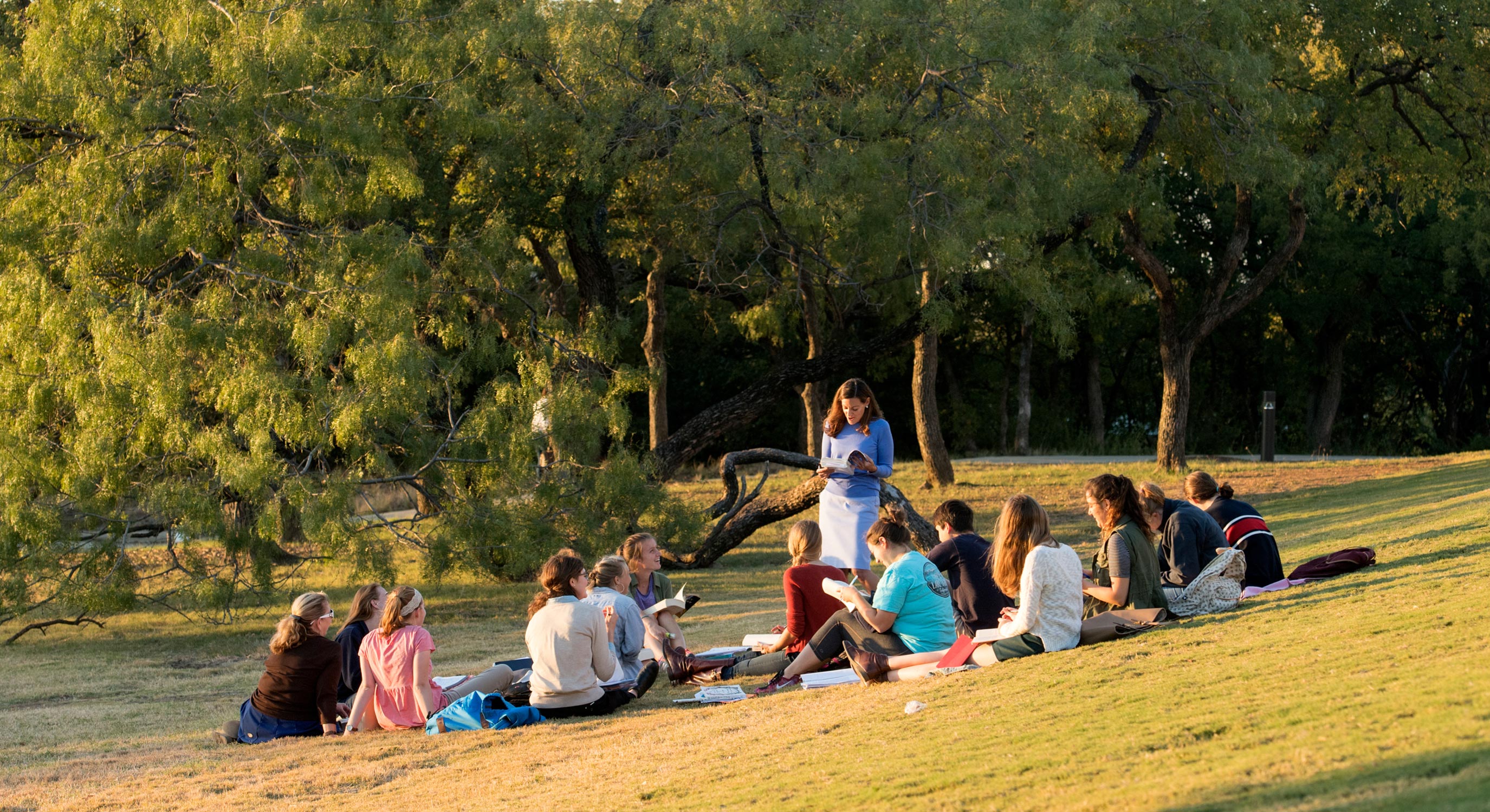 Professor teaching students on lawn