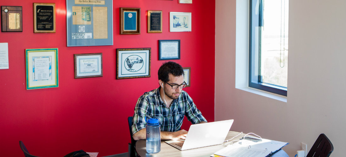 Student studies for an online master’s in finance exam in the library.