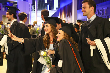 UDallas graduates celebrating with a seflie at commencement.